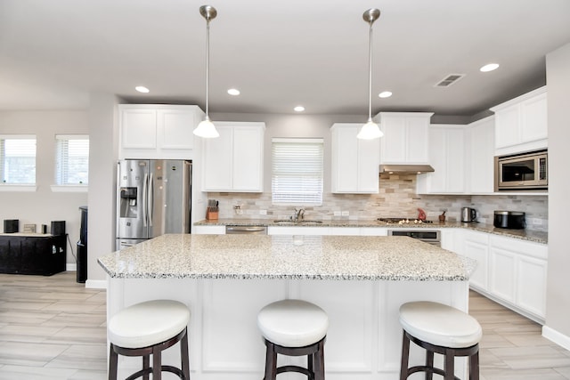 kitchen featuring a kitchen island, stainless steel appliances, and decorative light fixtures