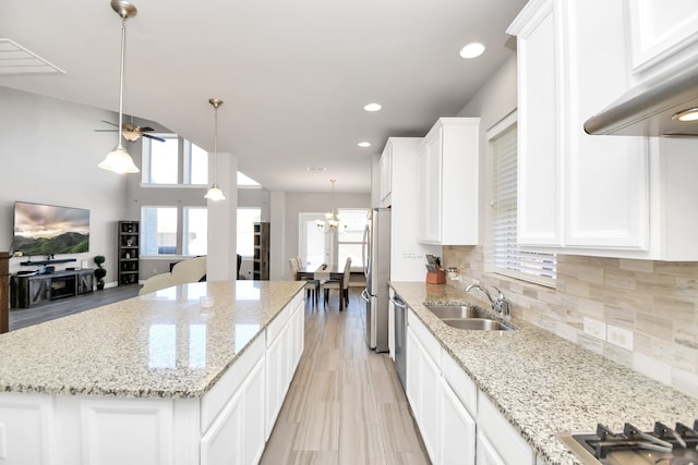 kitchen featuring a healthy amount of sunlight, white cabinetry, a kitchen island, and sink