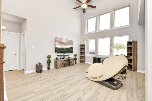 living room featuring a towering ceiling, light hardwood / wood-style flooring, and ceiling fan