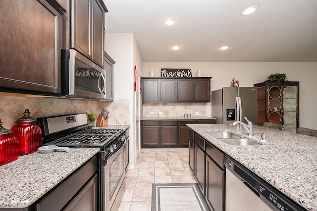 kitchen featuring decorative backsplash, light stone counters, stainless steel appliances, sink, and light tile patterned floors