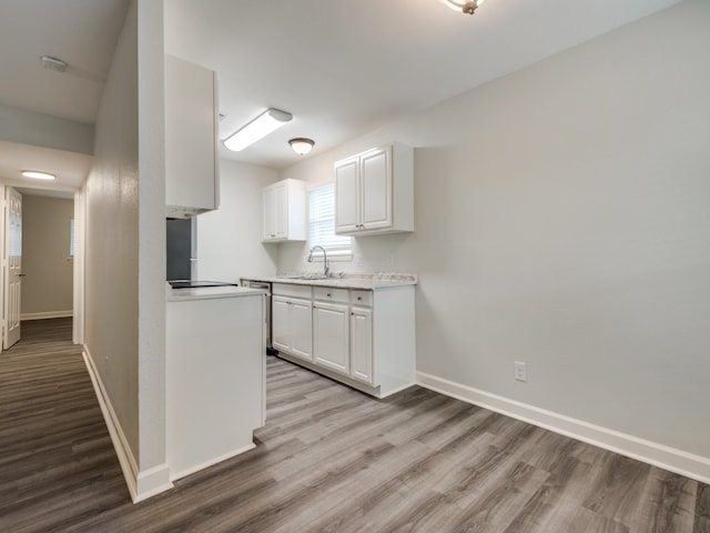 kitchen featuring light wood-type flooring, white cabinetry, and sink