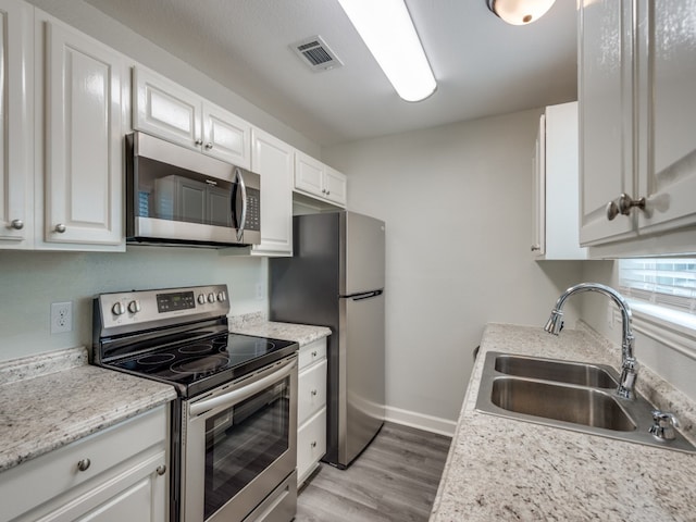 kitchen featuring white cabinetry, sink, light hardwood / wood-style floors, and appliances with stainless steel finishes