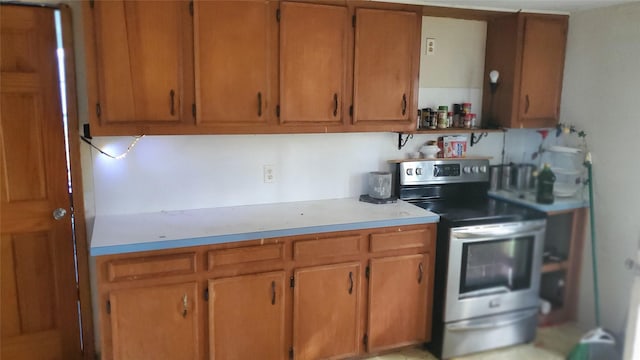809 8th Ave N, Texas City, TX 77590 - kitchen with stainless steel electric stove, light countertops, open shelves, and brown cabinetry