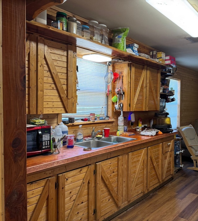 kitchen with wood walls, sink, and dark wood-type flooring