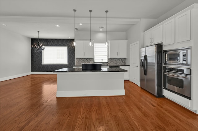 kitchen with appliances with stainless steel finishes, decorative light fixtures, white cabinetry, and dark hardwood / wood-style floors