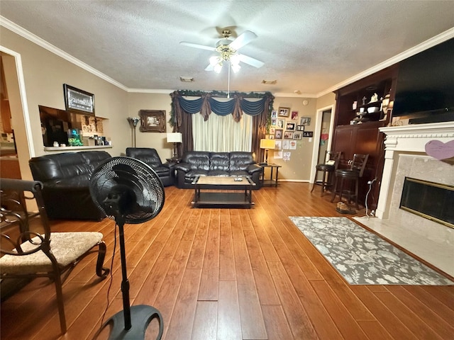 living room featuring crown molding, wood-type flooring, a textured ceiling, and a premium fireplace