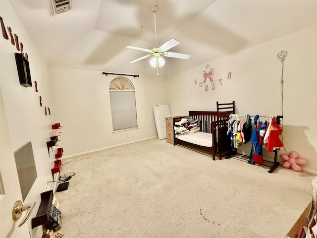 carpeted bedroom with ceiling fan, a crib, and vaulted ceiling