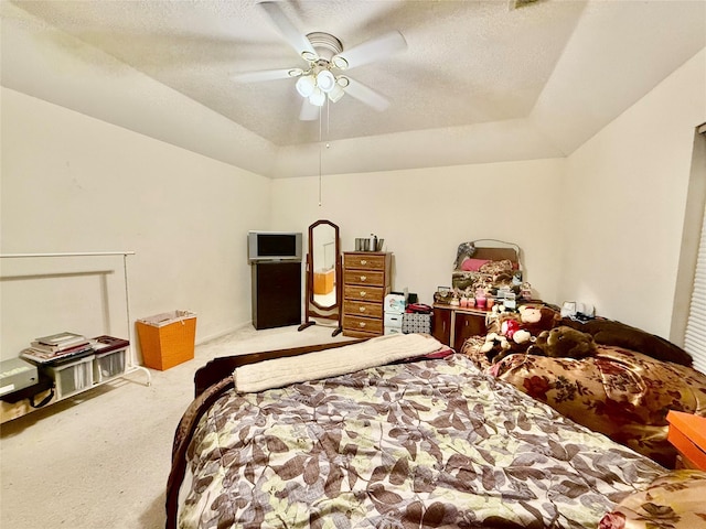 bedroom with carpet, a textured ceiling, a raised ceiling, and ceiling fan