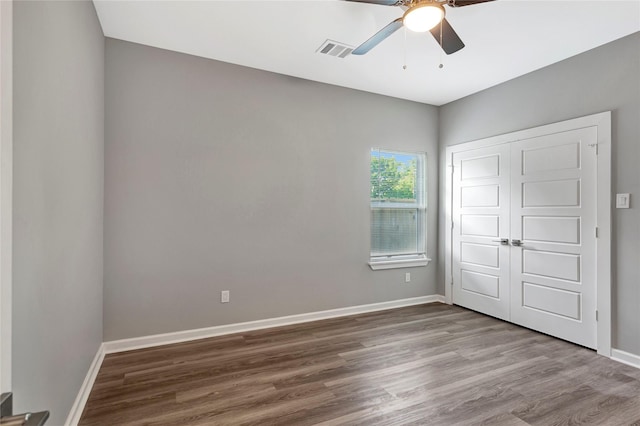 unfurnished bedroom featuring hardwood / wood-style floors, a closet, and ceiling fan