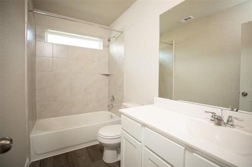 full bathroom featuring vanity, hardwood / wood-style floors, tiled shower / bath, and toilet