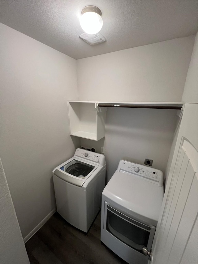 washroom with dark hardwood / wood-style flooring, washing machine and dryer, and a textured ceiling