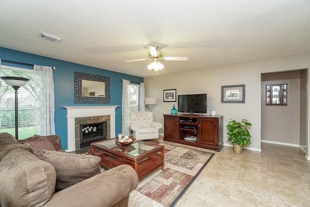 living room featuring plenty of natural light, ceiling fan, and a tile fireplace