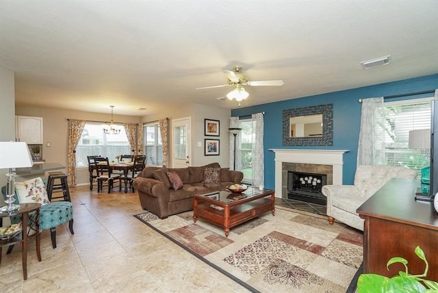 living room with a fireplace and ceiling fan with notable chandelier