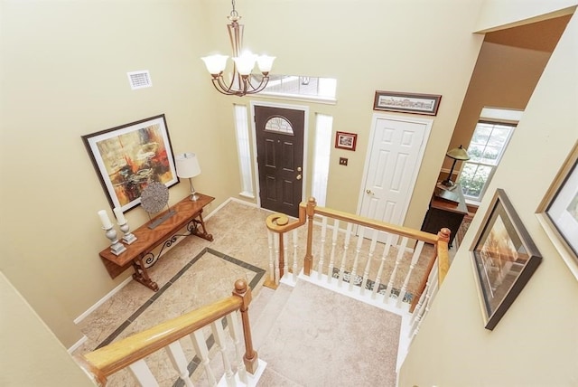 foyer featuring carpet floors, a towering ceiling, and a chandelier