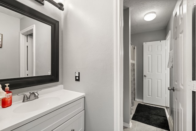 bathroom with tile patterned floors, vanity, and a textured ceiling