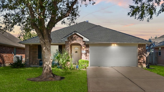 ranch-style home featuring a lawn, a garage, and central air condition unit