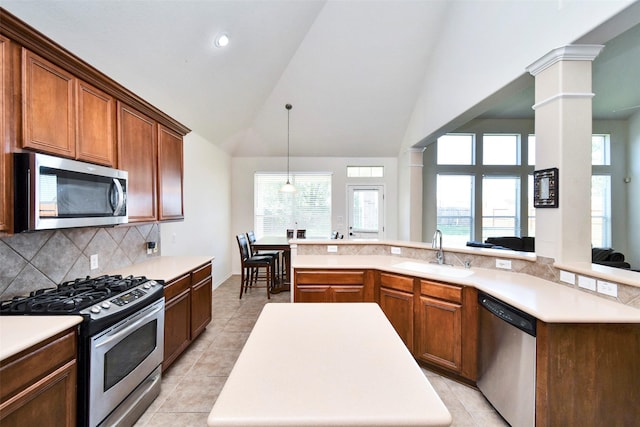 kitchen with stainless steel appliances, sink, a kitchen island, and ornate columns