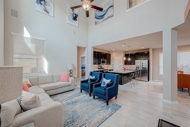 living room featuring ceiling fan and a high ceiling