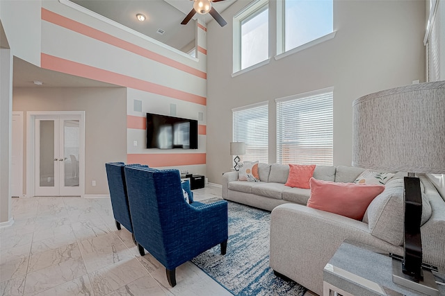 living room featuring plenty of natural light, ceiling fan, a towering ceiling, and french doors