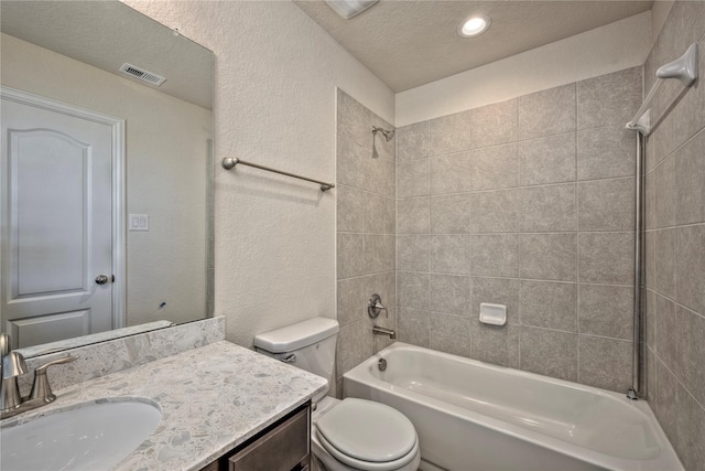 full bathroom featuring toilet, vanity, a textured ceiling, and tiled shower / bath