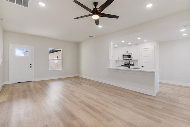 unfurnished living room featuring light hardwood / wood-style flooring, ceiling fan, and sink