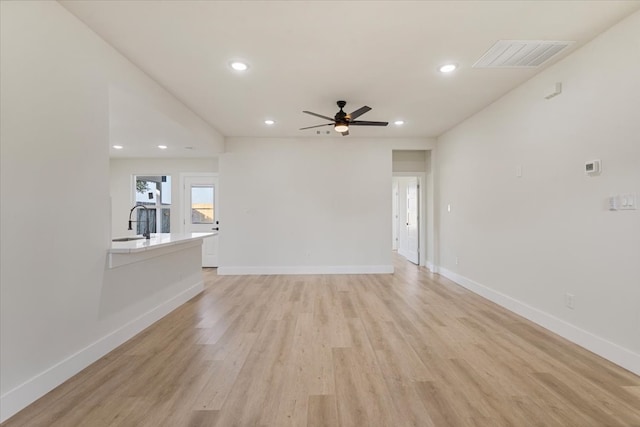 unfurnished living room with light hardwood / wood-style flooring, ceiling fan, and sink