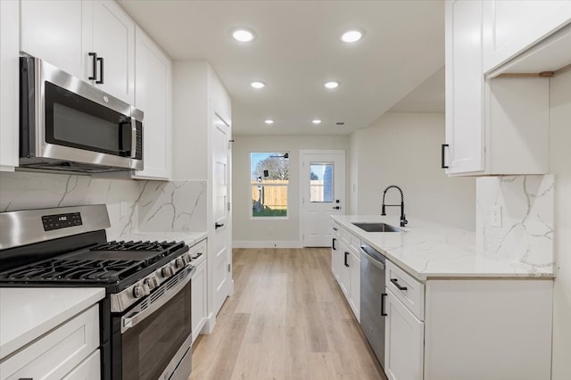 kitchen featuring white cabinetry, sink, stainless steel appliances, light stone counters, and light hardwood / wood-style floors