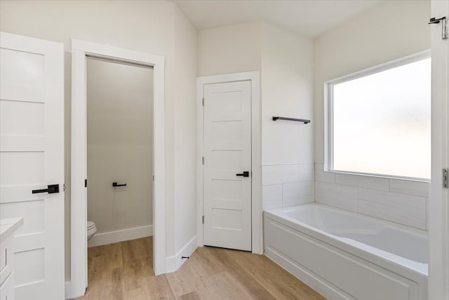 bathroom featuring a tub to relax in, hardwood / wood-style flooring, and toilet