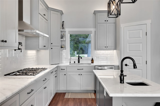 kitchen featuring light stone countertops, sink, pendant lighting, and wall chimney range hood