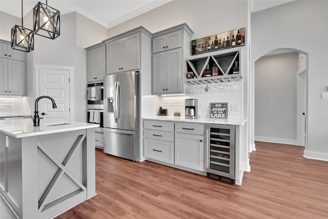 kitchen featuring backsplash, stainless steel appliances, sink, hardwood / wood-style floors, and wine cooler