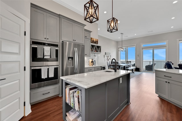 kitchen with stainless steel appliances, tasteful backsplash, an island with sink, decorative light fixtures, and gray cabinets