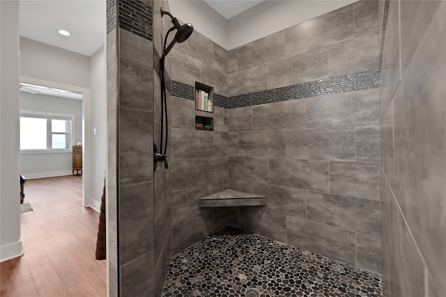 bathroom featuring hardwood / wood-style floors and a tile shower