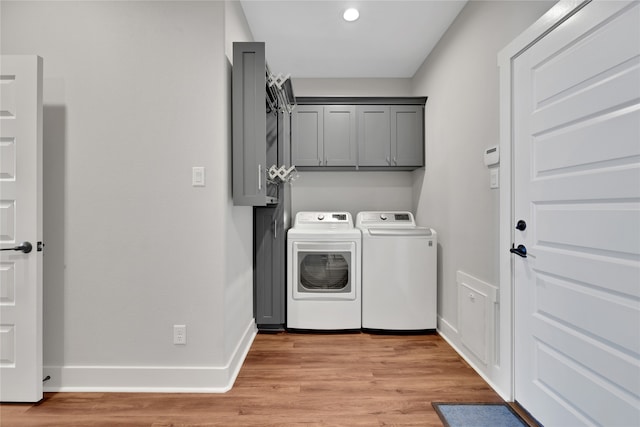 washroom with cabinets, washing machine and dryer, and light hardwood / wood-style flooring