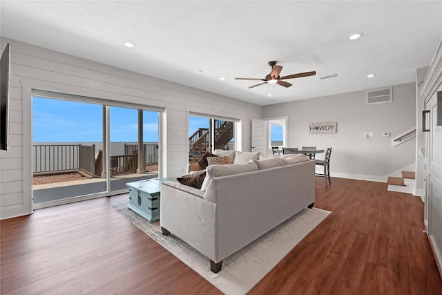 living room featuring dark hardwood / wood-style flooring, ceiling fan, and wood walls