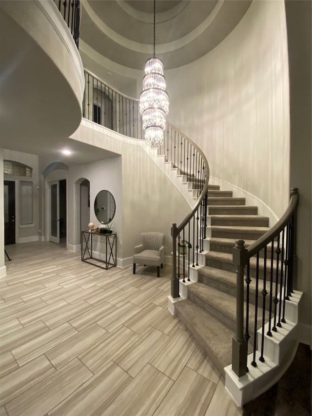 stairway featuring a chandelier, a high ceiling, and a tray ceiling