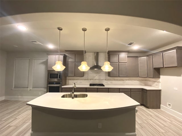 kitchen featuring hanging light fixtures, sink, appliances with stainless steel finishes, and an island with sink