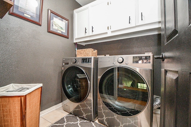 laundry room featuring cabinets, light tile patterned floors, and separate washer and dryer