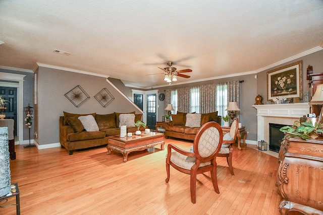 living room featuring a textured ceiling, ceiling fan, crown molding, and light hardwood / wood-style flooring