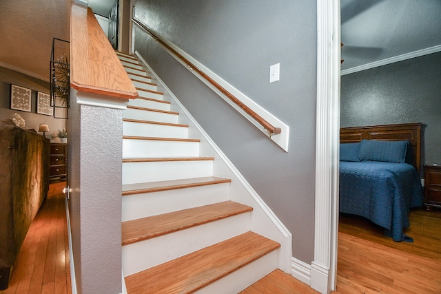 stairway featuring hardwood / wood-style floors and ornamental molding