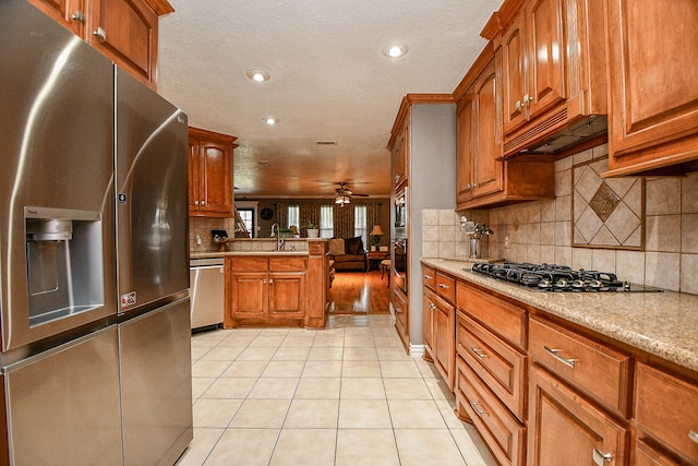 kitchen featuring ceiling fan, kitchen peninsula, a textured ceiling, light tile patterned flooring, and appliances with stainless steel finishes