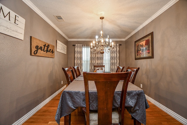 dining room with hardwood / wood-style flooring, a notable chandelier, and crown molding