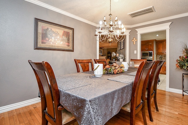 dining space with a chandelier, light hardwood / wood-style flooring, and crown molding