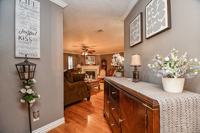 hall with a textured ceiling, light hardwood / wood-style flooring, and crown molding