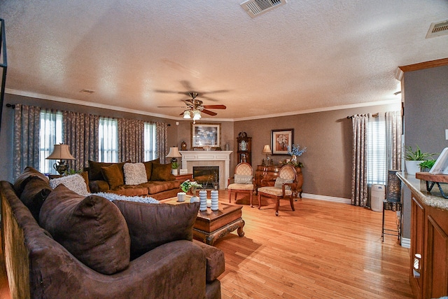 living room featuring a textured ceiling, light hardwood / wood-style floors, and crown molding