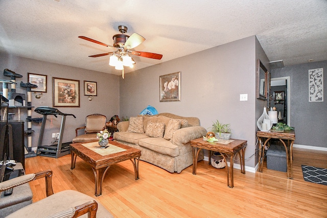 living room with ceiling fan, light hardwood / wood-style flooring, and a textured ceiling