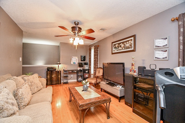 living room with ceiling fan, light hardwood / wood-style flooring, and a textured ceiling