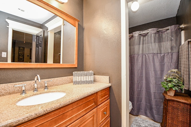 bathroom featuring vanity, toilet, and a textured ceiling