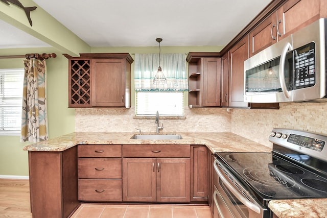 kitchen with pendant lighting, backsplash, sink, appliances with stainless steel finishes, and light stone counters