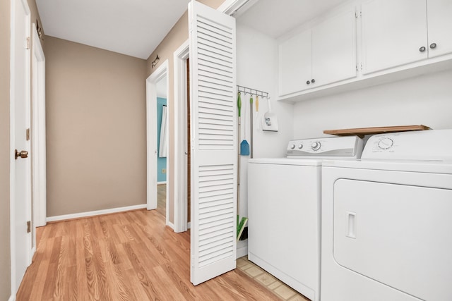 clothes washing area featuring cabinets, light wood-type flooring, and washing machine and clothes dryer