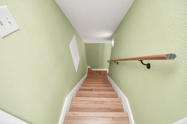 stairs with a textured ceiling and hardwood / wood-style flooring